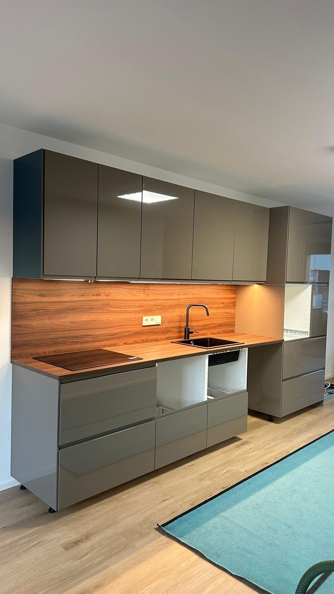Taupe Hochglanzküche mit Holzrückwand und Unterbaulicht